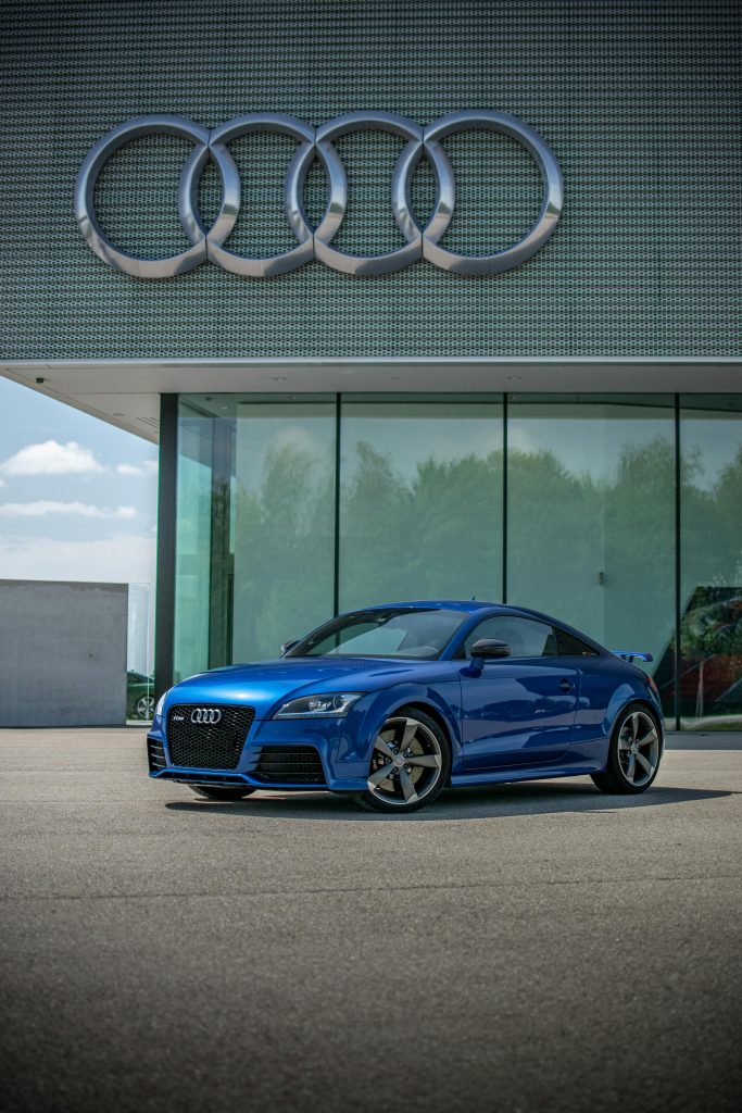 A sleek blue Audi sports car showcased in front of the Audi showroom.